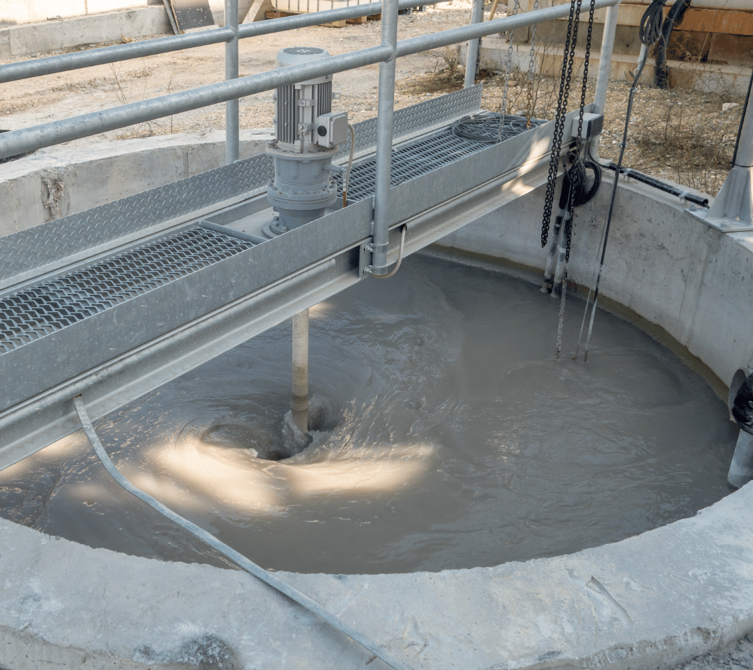 Grote tank met een elektrische mixer in een mengsel van zand en gemalen steen om beton te produceren
